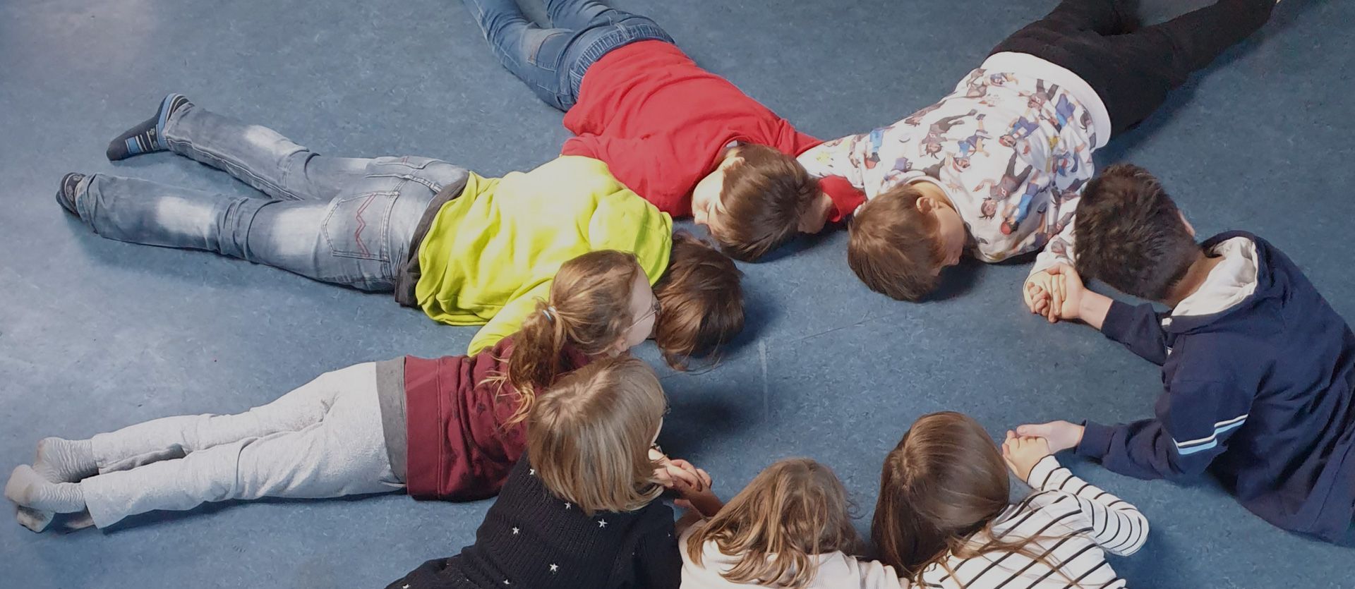 Kinder liegen im Kreis auf dem Boden