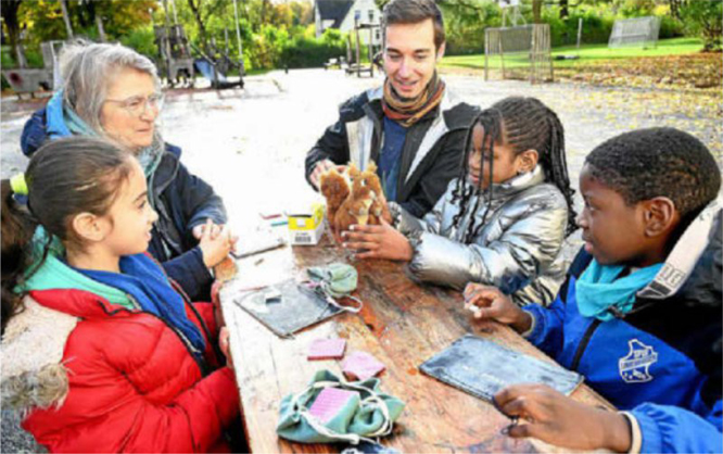 Kinder und Teamer des Waldsprachcamps sitzen zusammen an einem Tisch